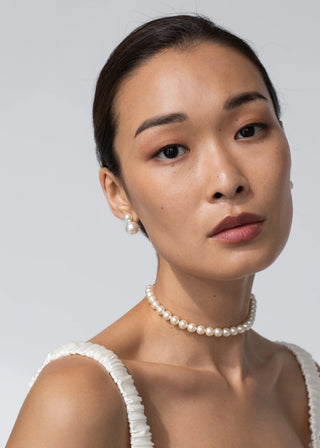 Model wearing the Pearl Ribbon Tie as a necklace, showcasing its elegant Austrian crystal pearls against a neutral background.