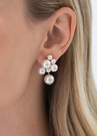 Pearl earrings worn by a person with blonde hair.
