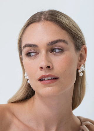 Woman wearing pearl earrings against a plain background