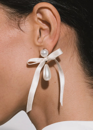 Formal jewelry piece with feminine ribbon flourishes and extended pearl silhouette for elevated designer styling