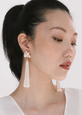 Long statement earrings featuring vintage-inspired pearl strands and sculpted cluster detailing, ideal for formal wear and high-fashion accessorizing.