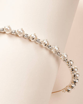 Pearl and crystal choker necklace on a mannequin neck against a beige background