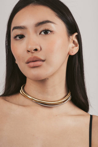 Woman wearing a gold necklace against a plain background