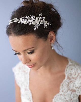 Bride wearing a decorative headpiece and earrings against a plain background