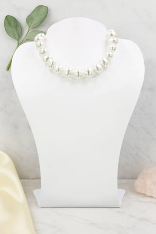 Pearl necklace on a white jewelry stand with a light background