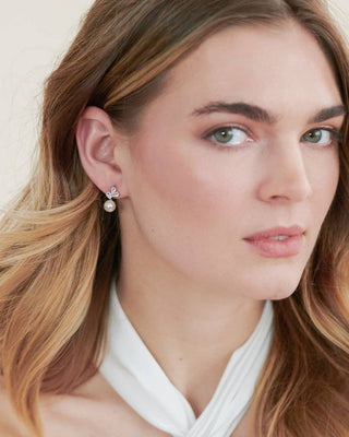 Close-up of a woman wearing pearl earrings with a neutral background