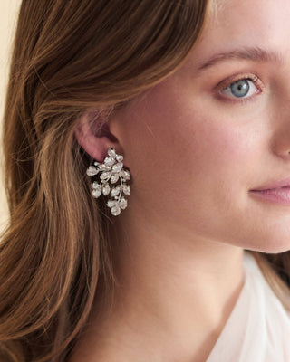 Close-up of a woman wearing a pair of silver earrings with a neutral background