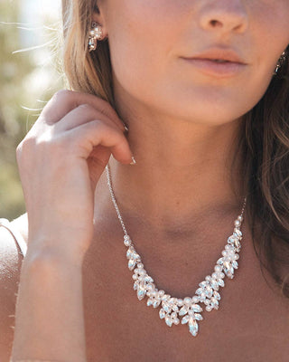 Close-up of a woman wearing a pearl necklace and earrings with a blurred background