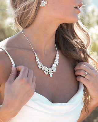 Bride wearing a delicate necklace with floral design, close-up of jewelry.