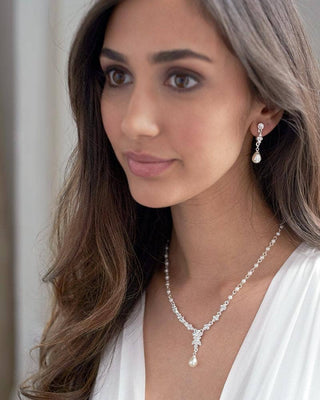 Woman wearing a pearl necklace and earrings with a white top.