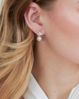 Close-up of a woman wearing pearl earrings with a white background