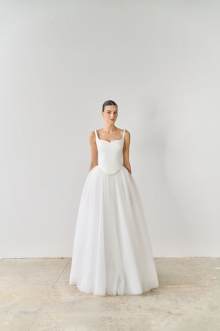 Woman wearing a white wedding dress against a plain background