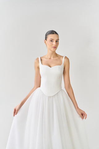 Woman wearing a white wedding dress against a plain background