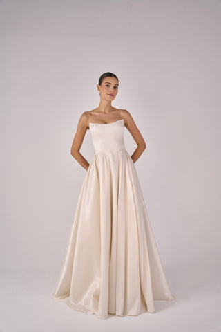 Woman wearing a strapless white gown on a plain background