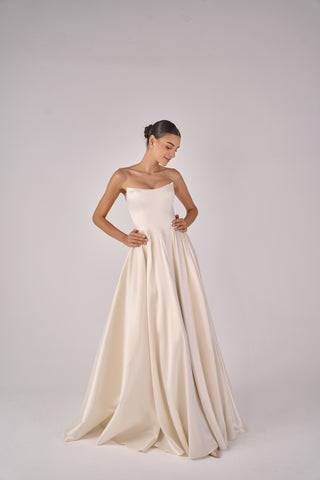 Woman wearing a strapless white gown on a plain background