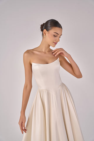 Woman wearing a white strapless dress against a plain background