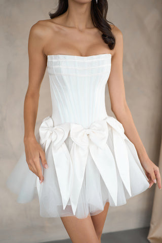 Chic strapless mini dress with a structured bodice and playful bow accents on the sides