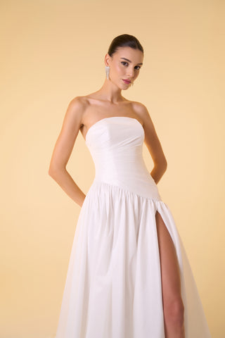 Asymmetrical dropped waist bridal gown with strapless neckline and thigh-high slit, perfect for a luxurious wedding day.