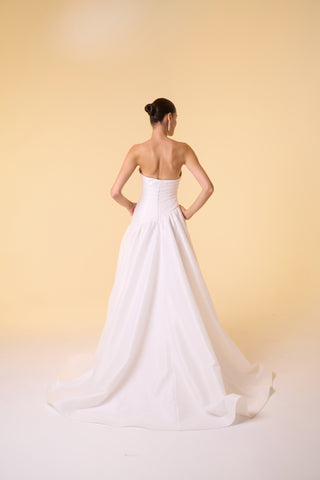 Modern bridal gown with a voluminous skirt, thigh-high slit, and expertly tailored strapless bodice for a timeless look.