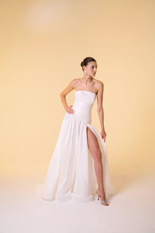 Designer bridal gown with a dramatic dropped waist, full-length silhouette, and refined strapless neckline.