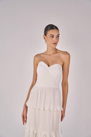Woman wearing a strapless white dress against a plain background