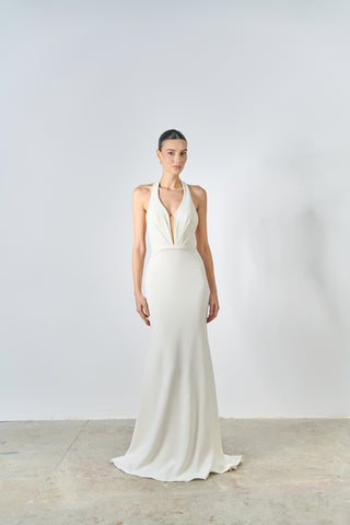 Woman wearing a white gown with a plunging neckline on a plain background