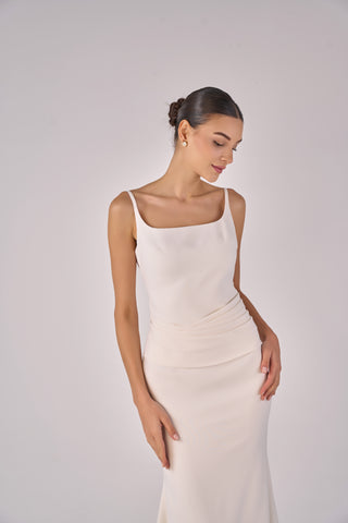 Woman wearing a white sleeveless dress against a plain background