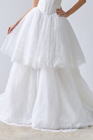 Woman wearing a strapless white wedding dress against a plain background