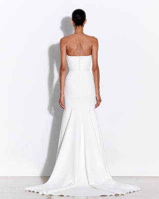 Back view of the Hartley wedding dress by Alex Perry, showing the extended train, concealed zip, and dome buttons. The dress features a strapless neckline and draped satin crepe.