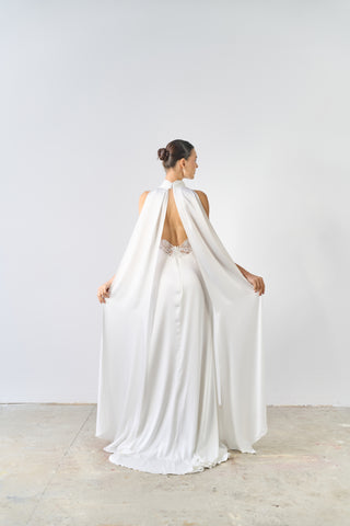 Woman wearing a white wedding dress with a cape in a minimalistic setting