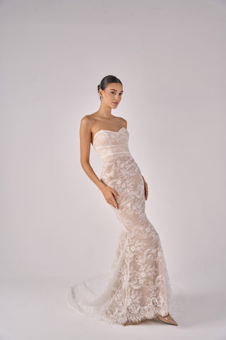 Woman wearing a strapless lace wedding dress on a white background