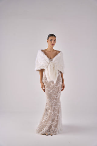 Woman wearing a lace dress and white shawl against a plain background