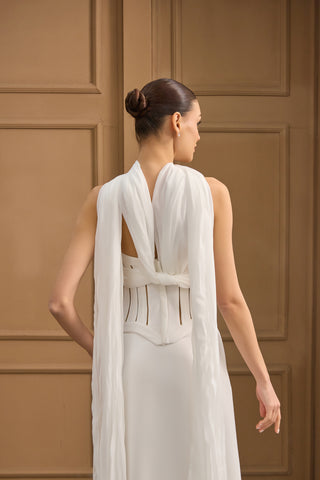 Striking bridal gown with a structured corset bodice, sleek silhouette, and draped scarf details for added drama.