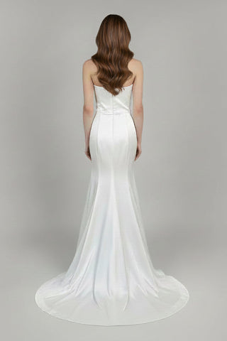 White wedding dress with a long train on a plain background