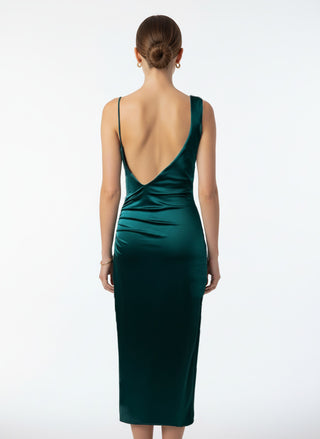 Woman wearing a green dress with a low back on a white background