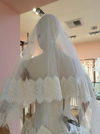 Elegant wedding veil with flowing silhouette, detailed lace border, and secure comb attachment