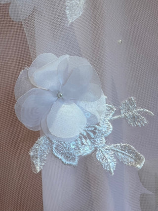 Close-up of an ivory silk floral applique on a cathedral length veil with scattered pearls.