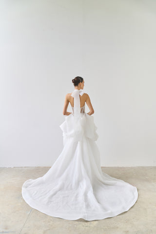 Woman wearing a white wedding dress with a long train in a minimalistic setting