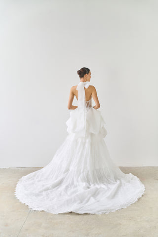 White wedding dress with a long train on a plain background