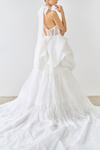 White wedding dress with a flowing train on a plain background
