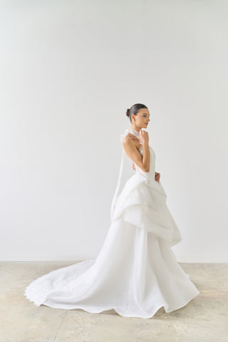 Woman wearing a white wedding dress with a long train in a minimalistic setting