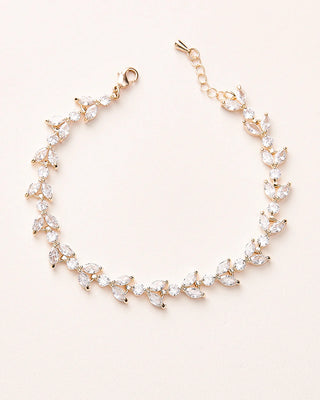 Gold bracelet with clear gemstones on a light pink background