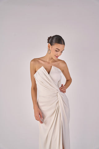 Woman wearing a white one-shoulder dress against a plain background