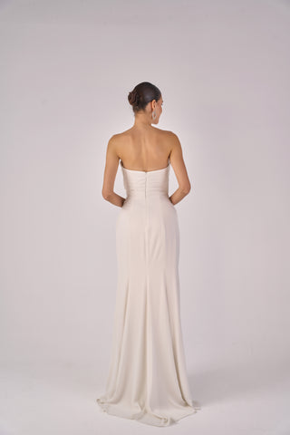 Woman wearing a strapless white gown on a plain background