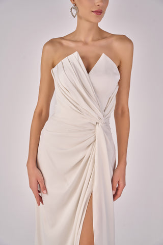 White strapless gown with a draped design on a plain background