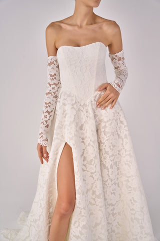 White lace wedding dress with long sleeves on a plain background