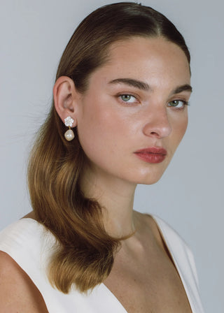Woman wearing pearl earrings against a plain background