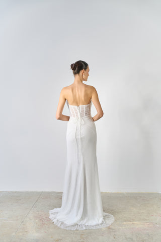 Woman wearing a white strapless gown against a plain background