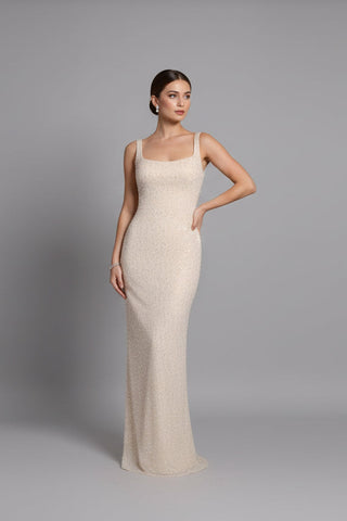 Woman wearing a beige evening gown against a gray background