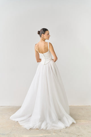 Woman wearing a white wedding dress against a plain background